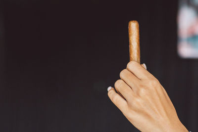 Close-up of hand holding leaf against black background