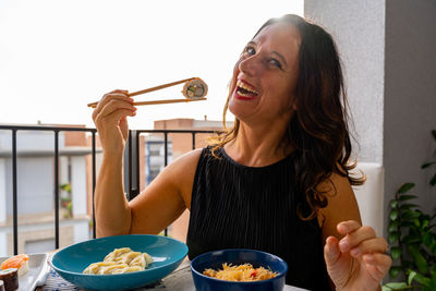 Portrait of smiling young woman having food at home