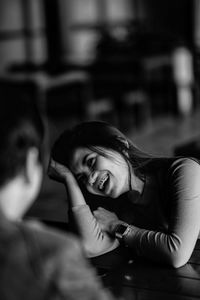 Smiling woman sitting by table at restaurant