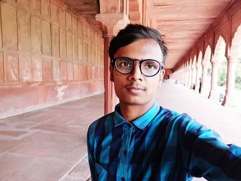 Portrait of smiling young man standing against wall