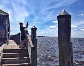 Birds perching on pier over sea