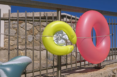 Multi colored balloons on railing against sky