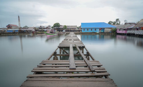 Pier by lake against sky in city