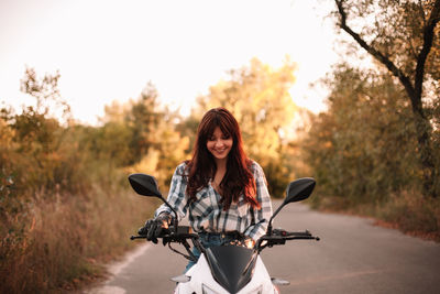 Portrait of young woman riding motorcycle on road