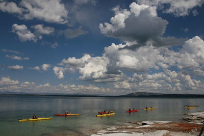 Boat sailing in sea against cloudy sky