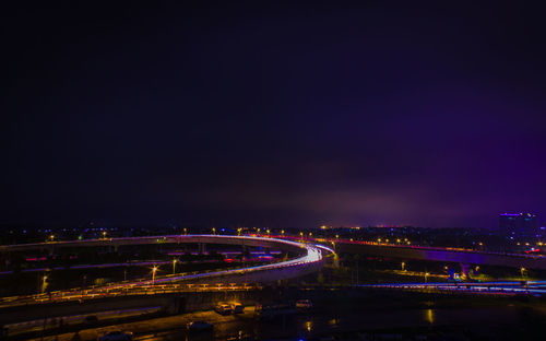 Light trails on highway in city against sky at dusk