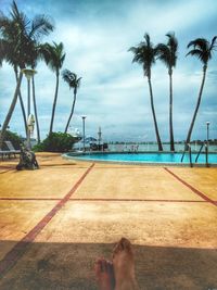 Low section of man by swimming pool against sky