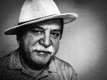 Portrait of senior man wearing hat sitting against wall