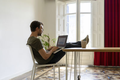 Young male entrepreneur working on laptop while sitting at table in office