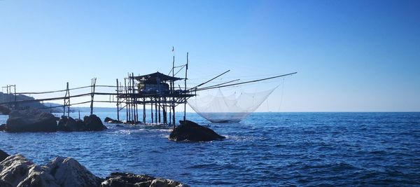 Sailboat in sea against clear blue sky