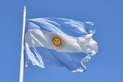 Argentine flag flying on a flagpole against a blue sky on a sunny day. patriotic symbol of argentina