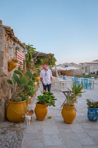 Man standing by potted plants against sky