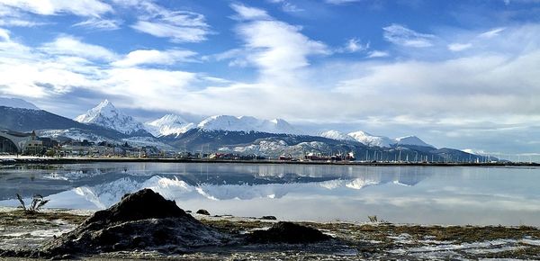 Scenic view of lake by snowcapped mountains against sky