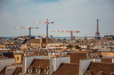 Close-up of buildings rooftops, cranes and eiffel tower on the horizon in paris. france.