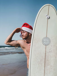 Man looking away while standing by sea against sky