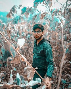 Portrait of young man standing by tree