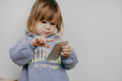 Portrait of cute girl holding gift against wall