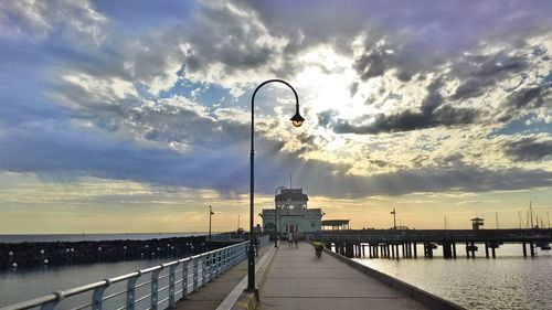 Pier on sea against cloudy sky