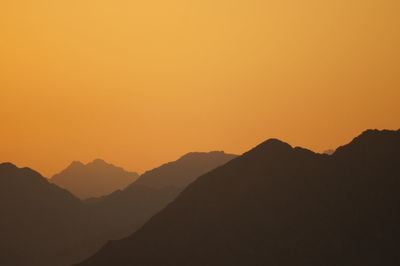 Scenic view of silhouette mountains against clear sky during sunset
