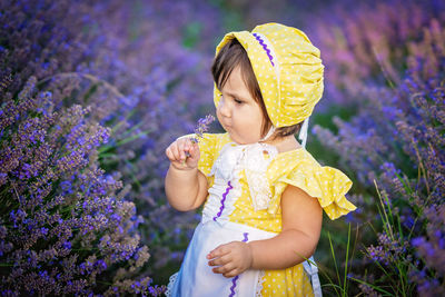 Close-up of cute girl smelling lavender flowers on field