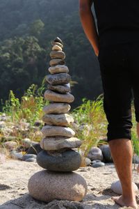 Low section of man standing by stones stacked on land
