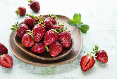 Fresh ripe delicious strawberries in a wooden bowl on a green wooden background