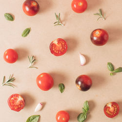 Creative arrangement of cherry tomatoes basil rosemary garlic oregano minimal food concept. flat lay