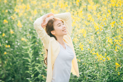 Smiling woman standing on yellow flowering field