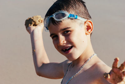 Close-up portrait of cute boy holding sand at beach