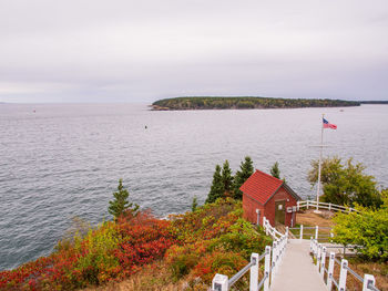 View from owl's head lighthouse in maine, usa, with fall foliage and an american flag.