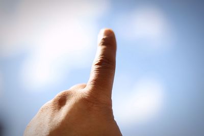 Close-up of human hand against sky