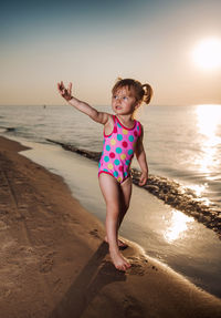 Cute girl gesturing while standing on shore at beach