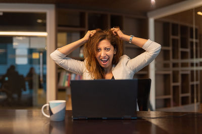 Young woman using laptop while sitting on table