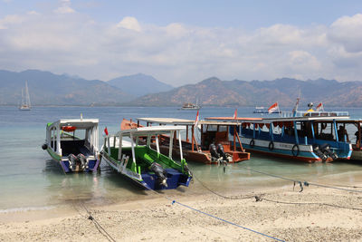 Boats moored at beach against sky