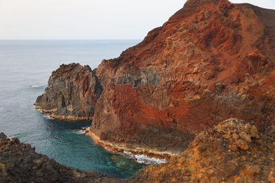 Rock formations on shore by sea against sky