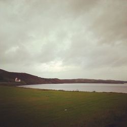 Scenic view of grassy field against cloudy sky