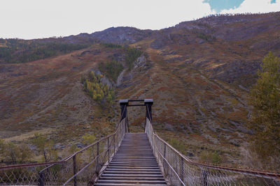 Footbridge amidst mountains against sky