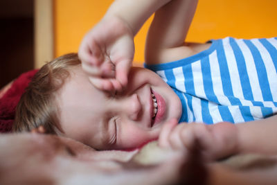 Close-up of boy rubbing eyes while lying on bed