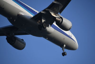 Low angle view of airplane against clear blue sky