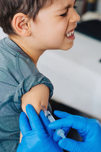 Cropped hands of doctor injecting syringe to boy in hospital