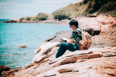 Man sitting on rock looking at shore