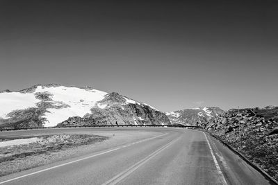 Road leading towards mountain against sky during winter