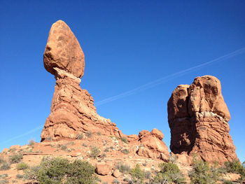 Low angle view of rock formations against clear blue sky