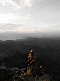 People sitting on mountain against sky