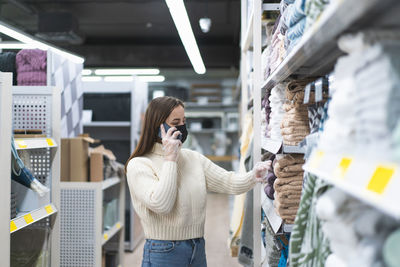 Woman wearing face mask and protective gloves in store uses phone. today people lifestyle concept