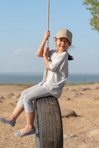 Portrait of girl sitting on tire at beach