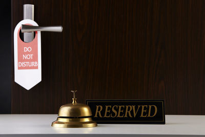 Close-up of information sign on table against wall