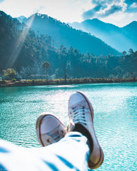 Low section of person in sea against mountains