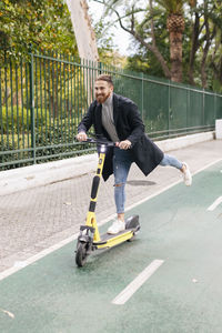 Young man enjoying electric push scooter ride on bicycle lane
