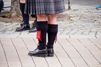 Low section of girl and boy wearing kilt while standing on street